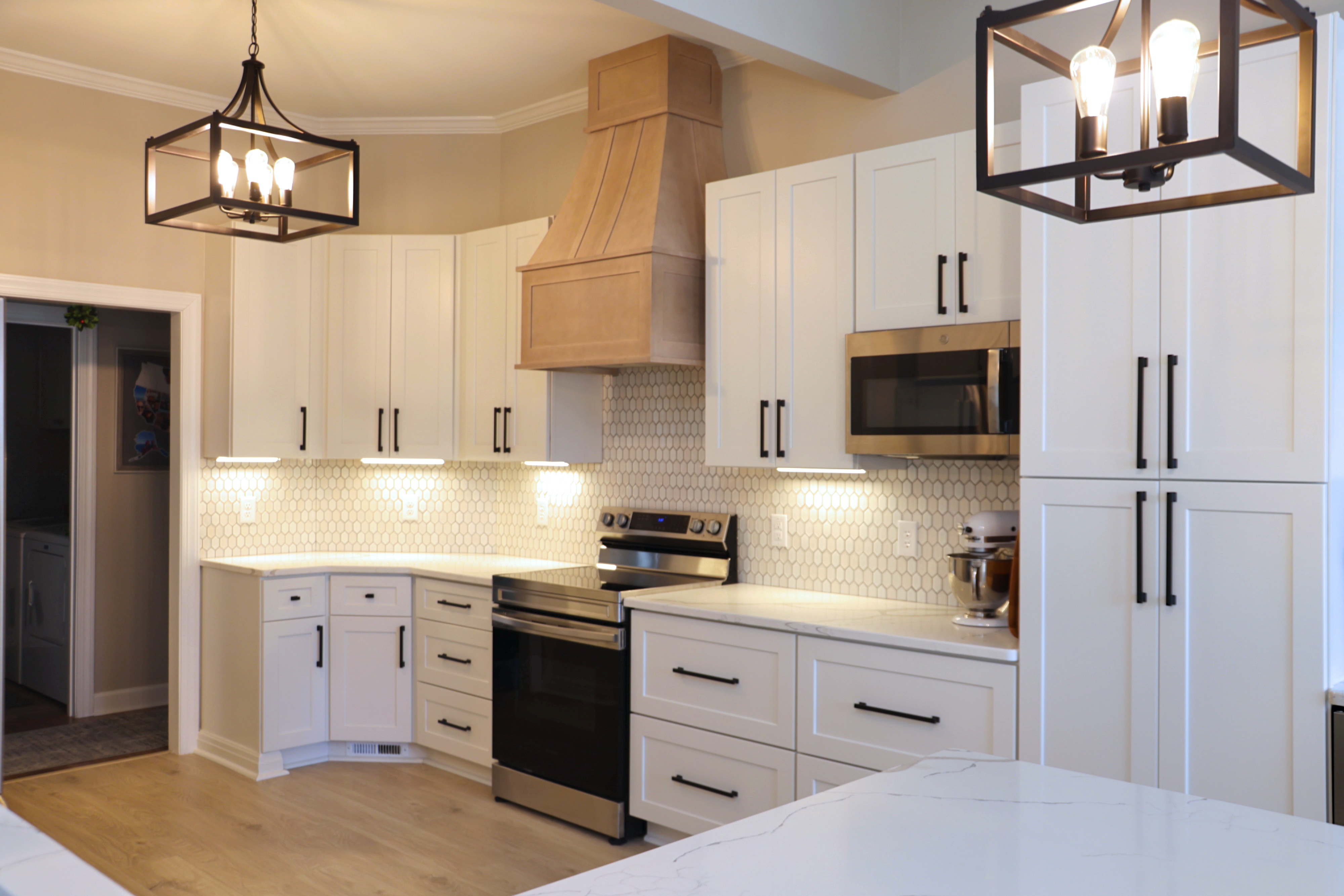 white kitchen cabinets with natural wood hood over stove