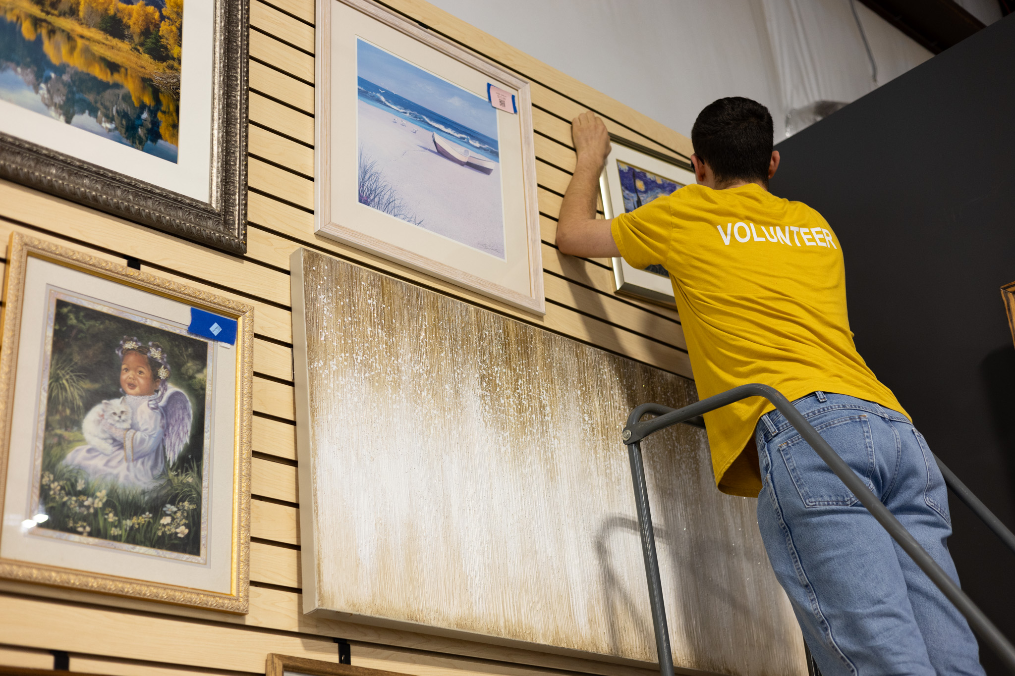 core volunteer Kai Christopher organizing wall art