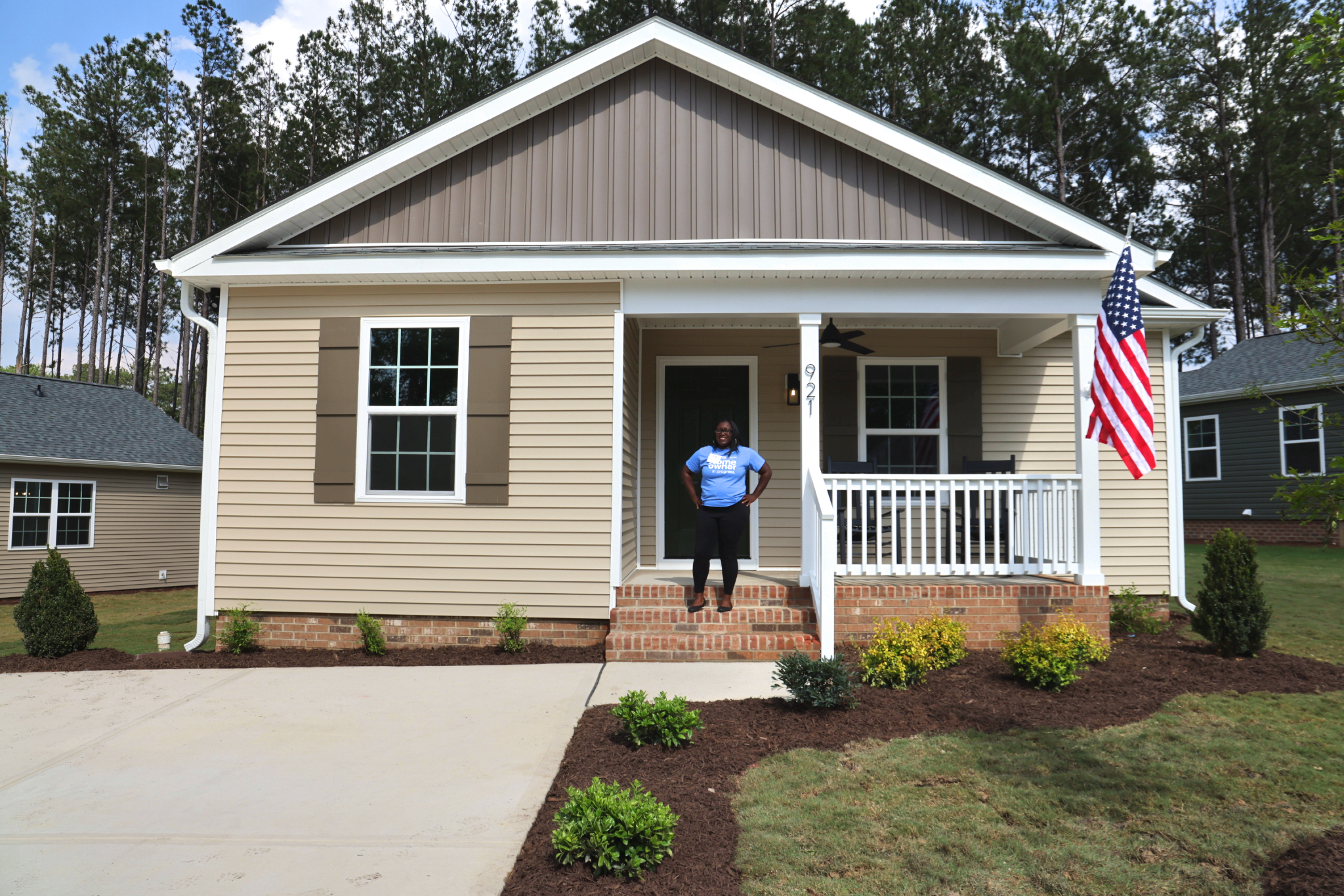 Homeowner Quanesha Banks stands outside her Habitat home, built by Homestead Building Company and McNeill Burbank during the '25 Home Builders Blitz.