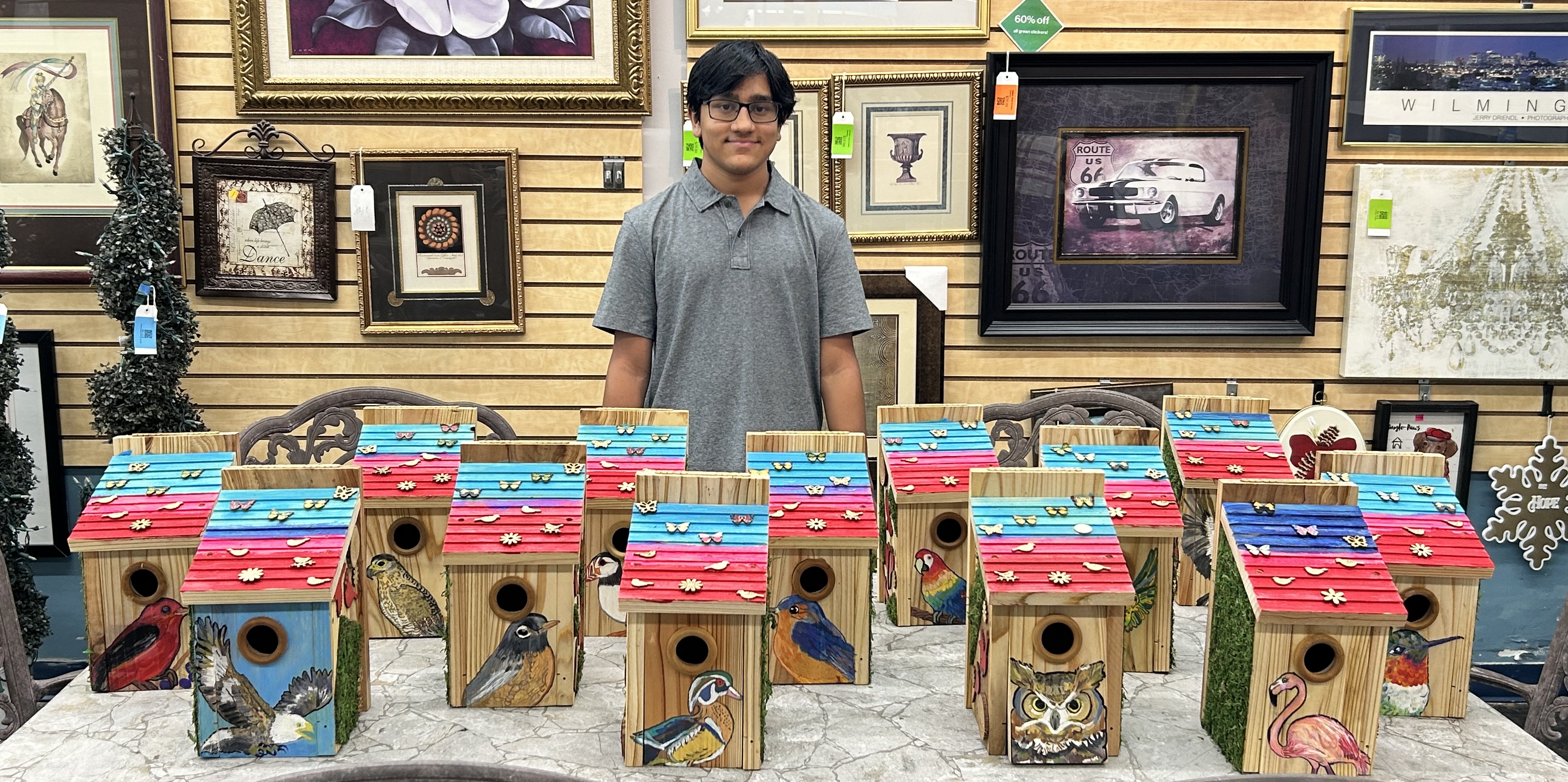 High school student standing behind thirteen birdhouses he crafted to donate to the Cary ReStore