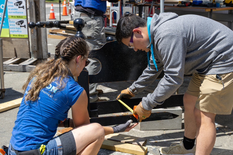 Student Volunteer measures bed frame with help of Cary ReStore staff