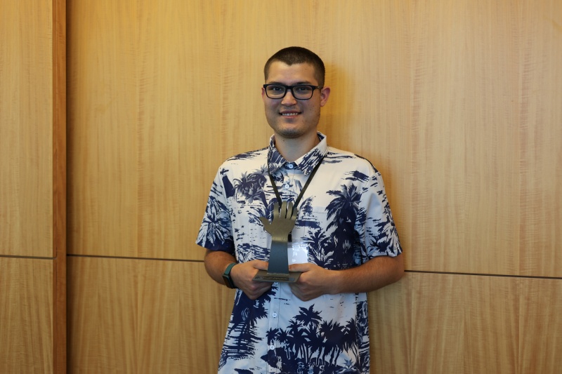 Core volunteer Kai Christopher holding award at ceremony